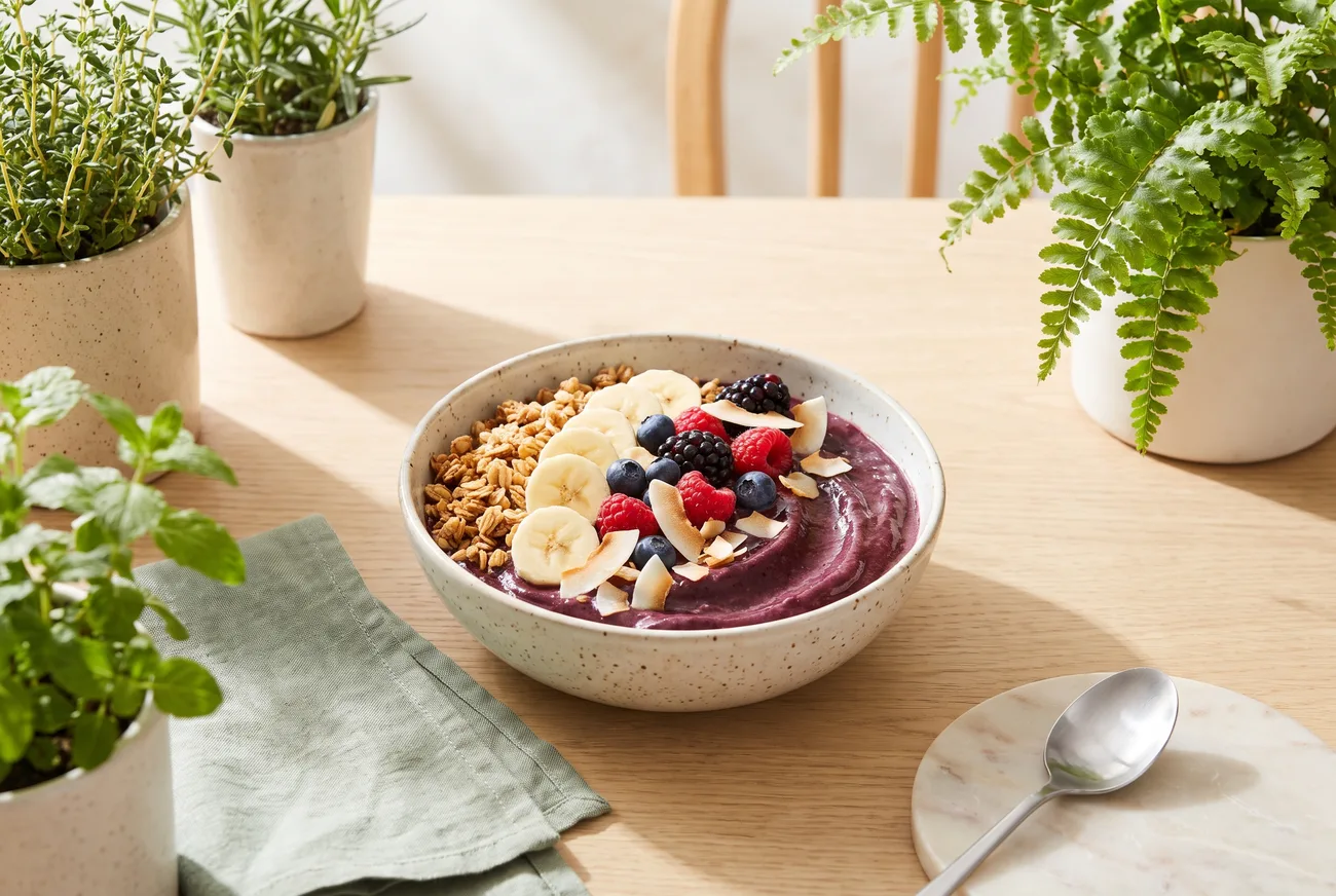An açaí bowl topped with granola, banana slices and mixed berries